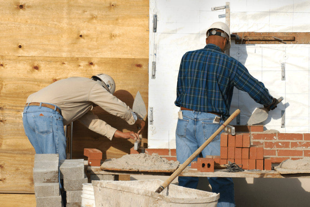 2 masons building measuring and building a brick accent walls